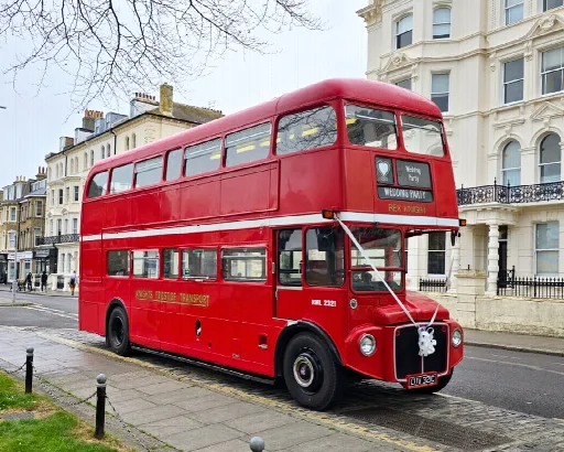 Red Routemaster double decker bus decorated with white wedding ribbons