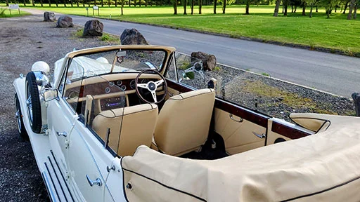 Vintage convertible car with roof open showing cream leather interior