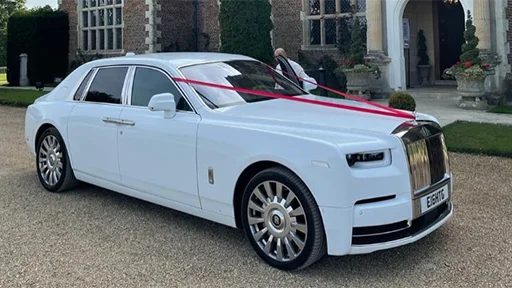 Modern white Rolls-Royce Phantom 8 dressed in red ribbons on wedding duties