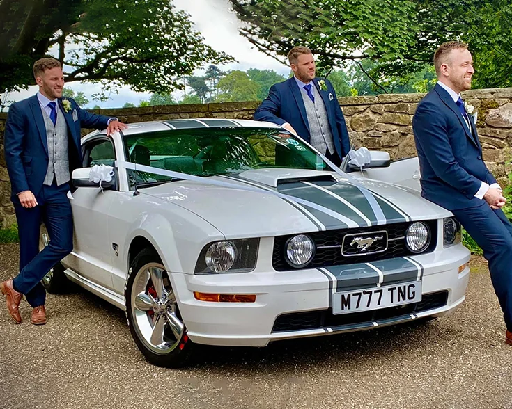 Groom and groomsmen with Ford Mustang modern sport car with ribbons and bows