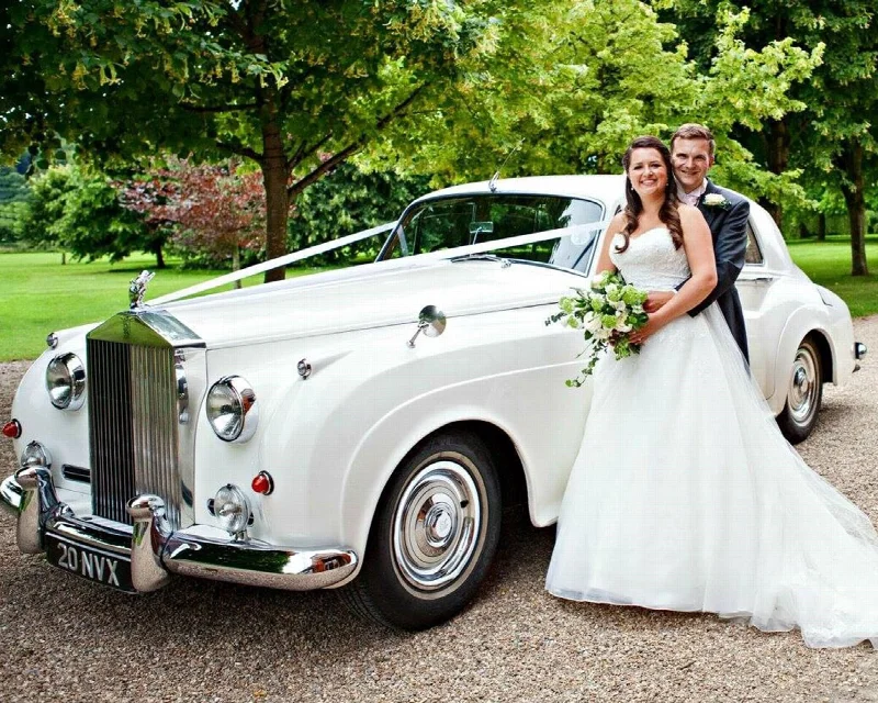 Happy Couple standing beside a white classic Rolls-Royce Silver Cloud