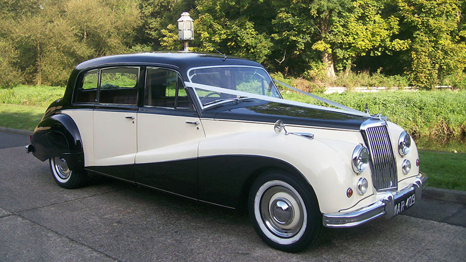 Armstrong-Siddeley Limousine in black and ivory standing in front of forest background