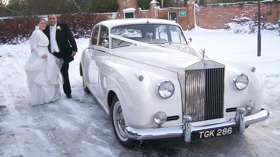 Rolls-Royce Silver Cloud on a winter wedding in uxbridge with snow and bride & Groom on front of the vehicle