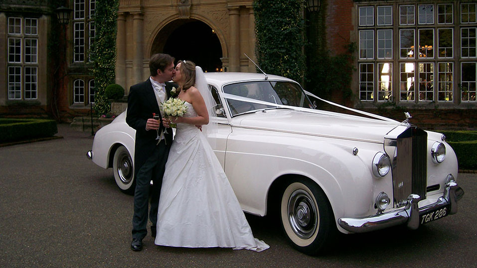 Classic Rolls-Royce Silver Cloud with happy couple in front of the vehicle