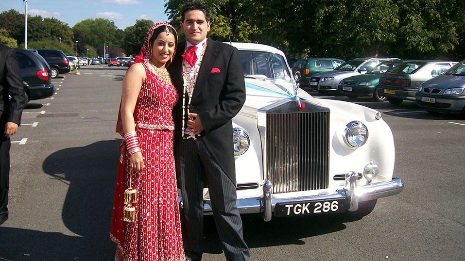 Asian Couple on the day of their wedding ion front of the Rolls-royce they've hired