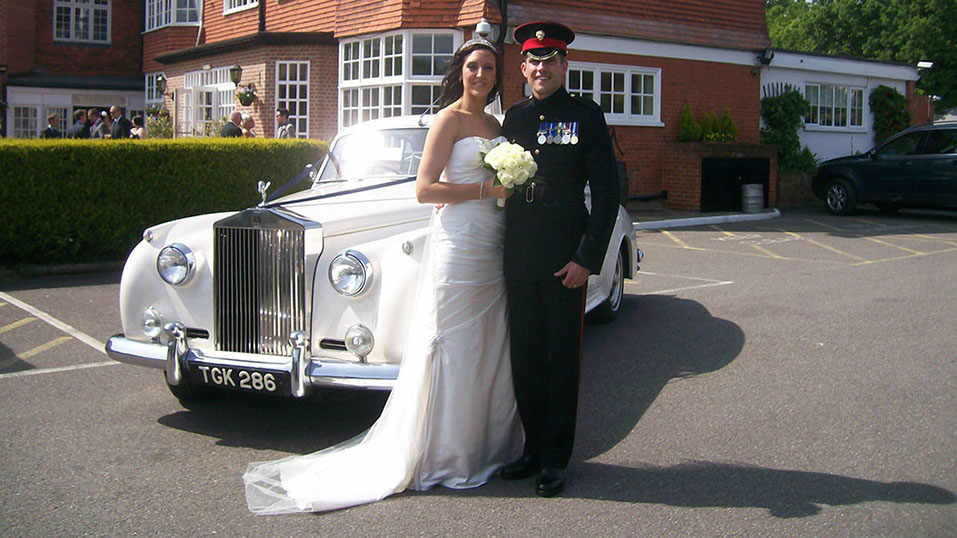 Classic Rolls-Royce with military groom and his bride posing for photos
