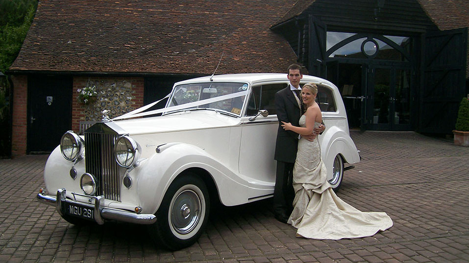Couple standing by their vintage rolls-royce for photos