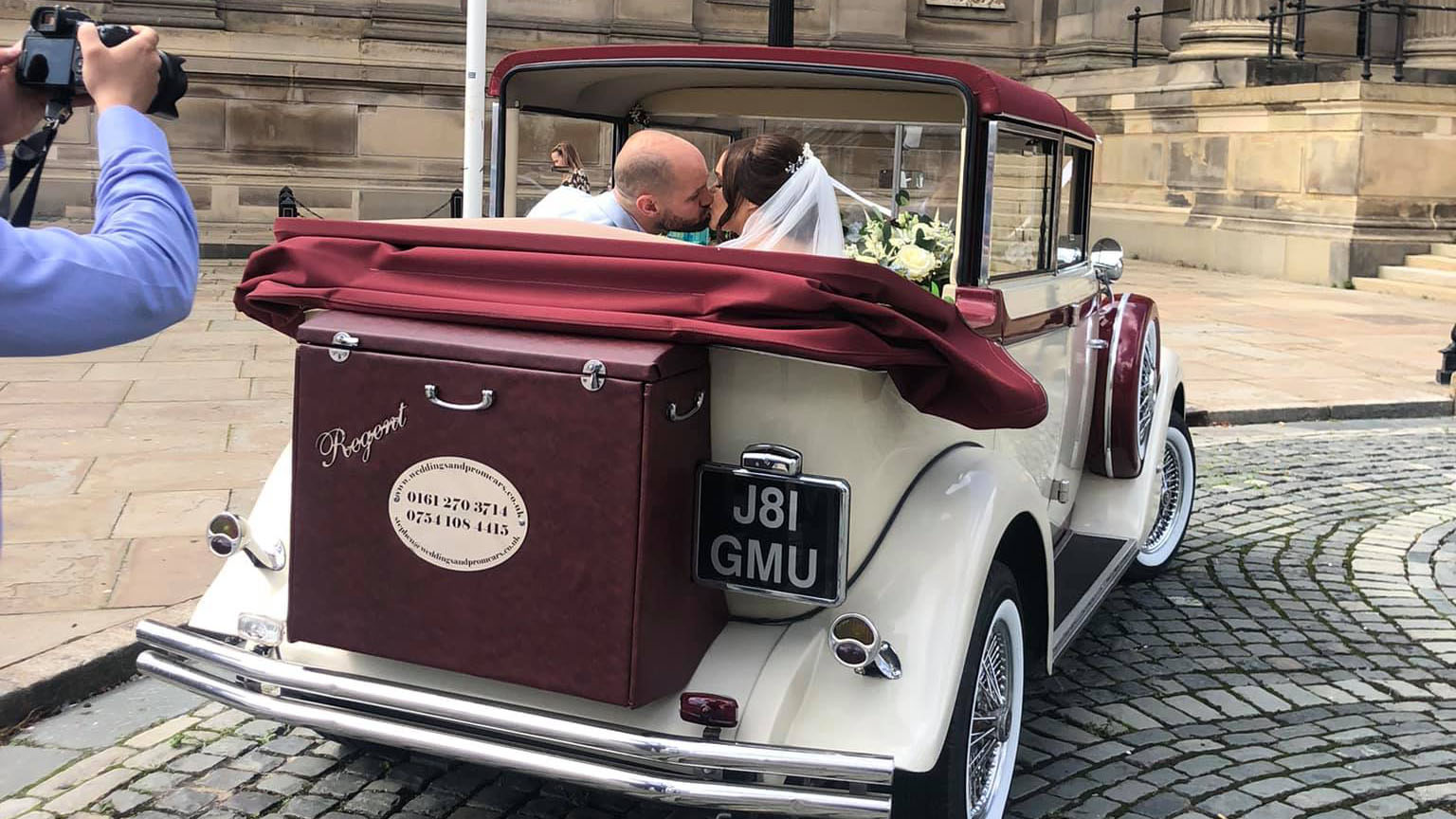 Newly Wed Couple kissing in the back of the convertible car they've hired from their wedding in Liverpool