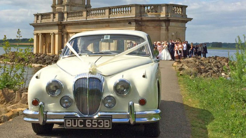 White Classic Jaguar Mk2 with the wedding party having some photos with the car