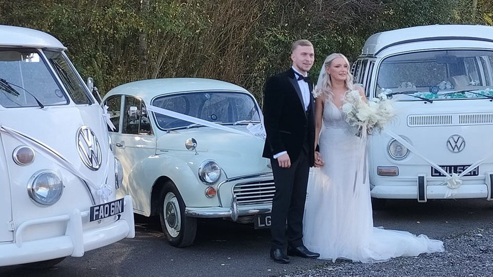 Couple having their photos taken next to the fleet of Classic VW's they've arrived for their wedding in West Yorkshire
