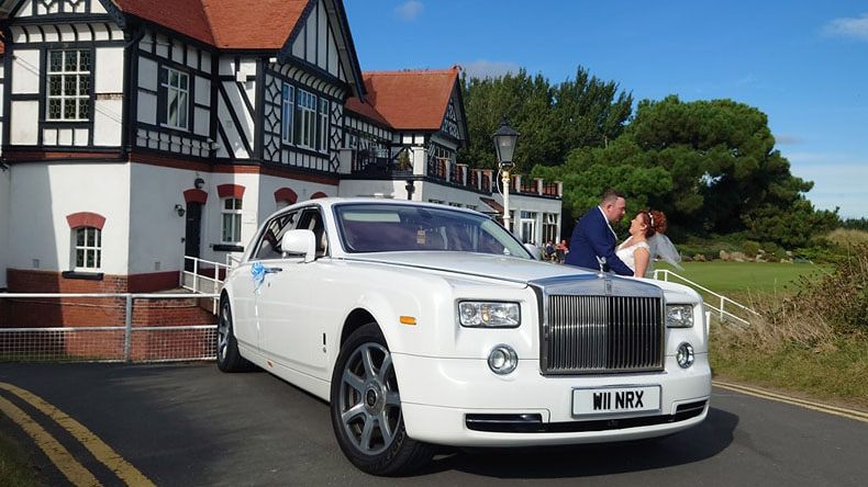 Bride and Groom kissing in front of their White Rolls-Royce