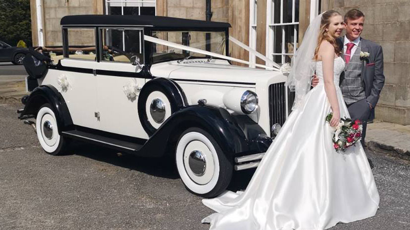 Bride and Groom having photos taken by their vintage car 