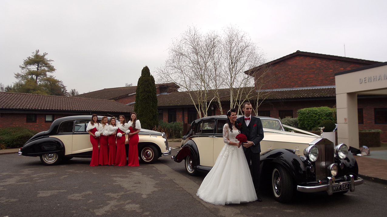 bride and groom with the two matching classic cars they have hired