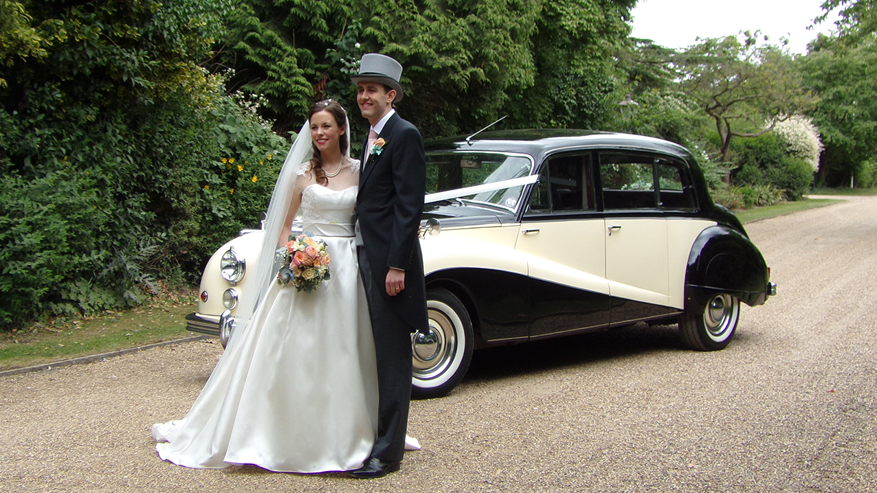 bride and groom in front of the black and ivory classic limousine