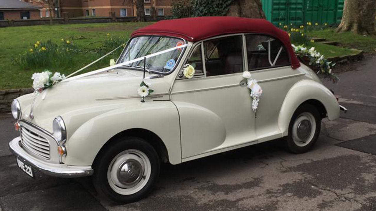 Morris Minor side view with roof up and white wedding ribbons