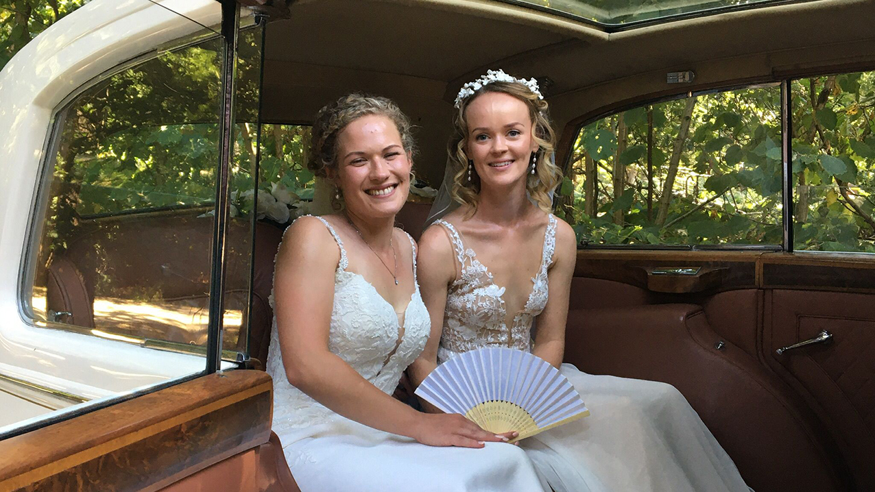 two brides having photos taken inside the vintage rolls-royce