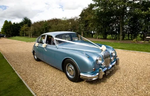Silver Blue Classic Daimler in Bedfordshire dressed with white ribbons and a small bow on top of the chrome grill