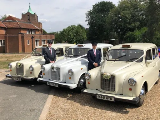 Three Classic Taxi Cabs decorated with Ribbons and flowers on front grill with their chauffeurs standing by the cars. chauffeurs are wearing dark grey suit and chauffeur's hat