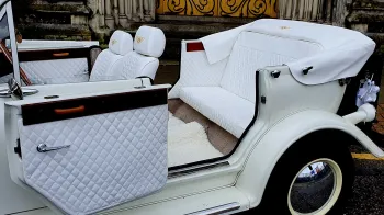 Rear Door of Beauford is open to show large leg room in the rear passengers seats, white carpet and white leather interior