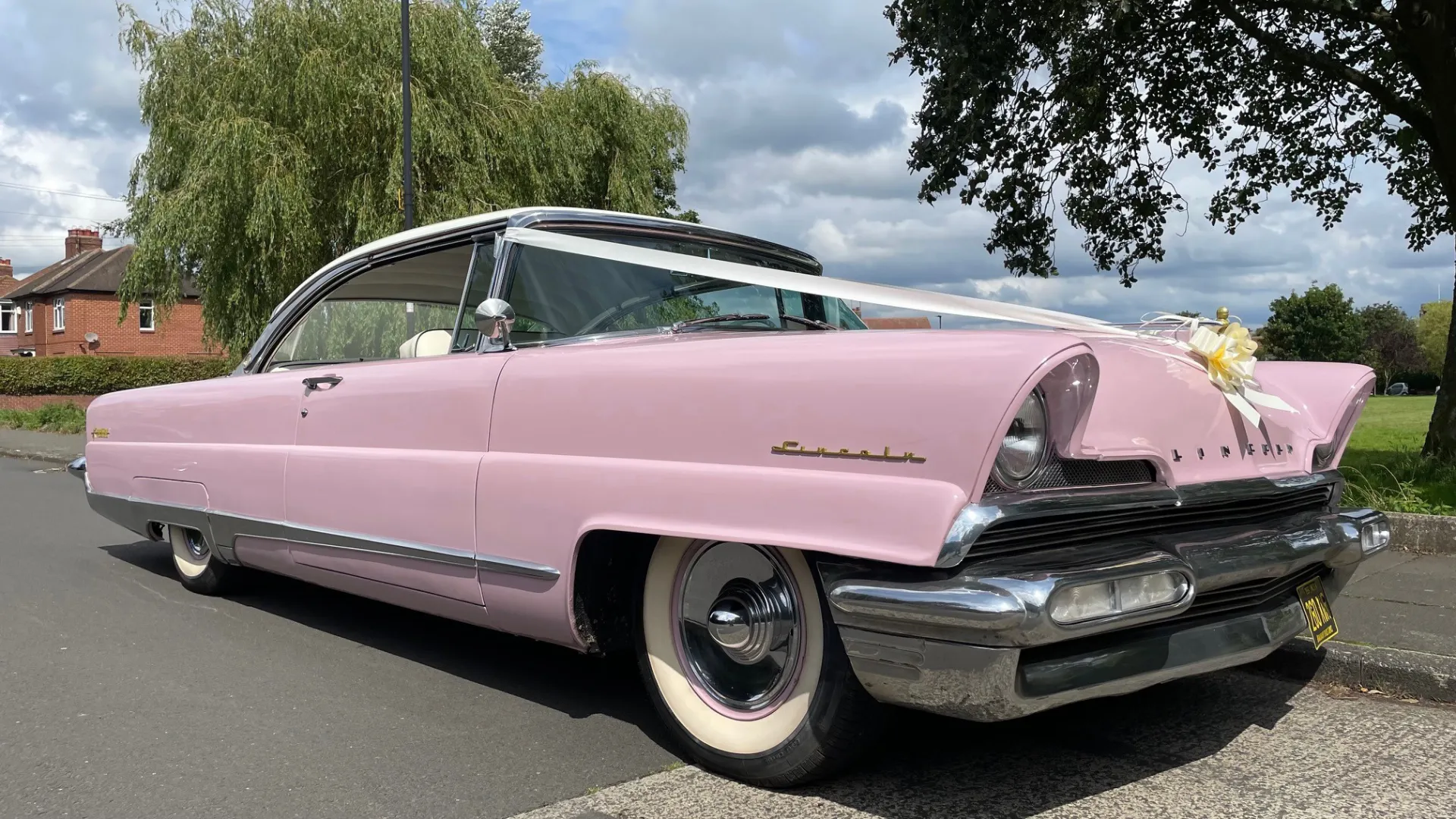 Pink Classic American Lincoln Premiere Car dressed with traditional White ribbons on its front bonnet