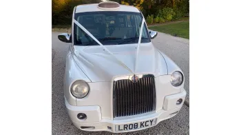 Front view of a Modern White taxi Cab dressed with White Ribbons and Orange Taxi Sign on top of roof