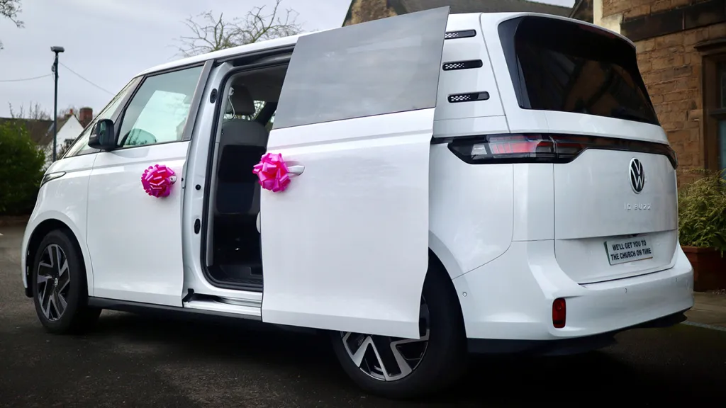 Rear side view with rear sliding door open showing the large door entrance and decorated with pink ribbons on door handles