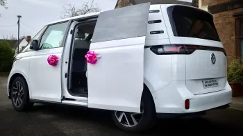 Rear side view with rear sliding door open showing the large door entrance and decorated with pink ribbons on door handles