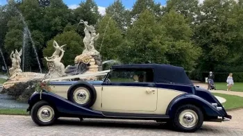 Left side view of vintage car with roof up and white ribbons