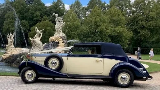 Left side view of vintage car with roof up and white ribbons