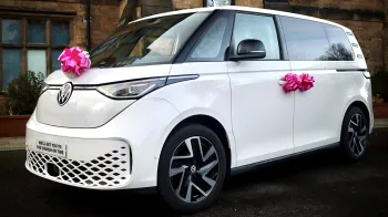 White Electric VW ID Buzz decorated with Pink bows on the front of the car and door handles