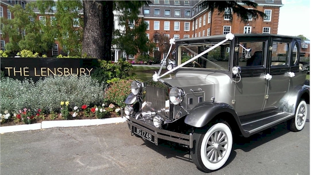 Side view of Imperial decorated with White ribbon. Car has light silver on its body and darker silver grey on top half