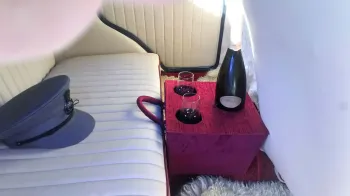 inside rear seating area with chauffur's hat on the rear bench seat, mini bar in the middle of the seat