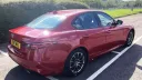 Rear side view of Alfa Romeo Giulia in Red with black and silver wheel arches