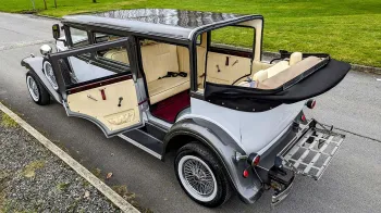Aerial view of vintage limousine with roof open and rear cabin door open shwoing cream interior and red carpet