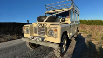 Left front view of Classic Landrover with white wedding ribbons decoration accross its bonnet