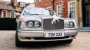 Full front view of silver bentley dressed with Big White Bow on top of the chrome grill
