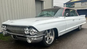 Front Side view of White Cadillac with large Chrome Alloy wheels and bumper