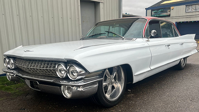 Front Side view of White Cadillac with large Chrome Alloy wheels and bumper