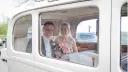 Bride and Groom sitting inside the Vintage Daimler. Bride is holding her bridal bouquet