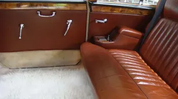 Rear inside cabin of a Classic Daimler showing the rear bench seat in a Tan Leather and White carpet