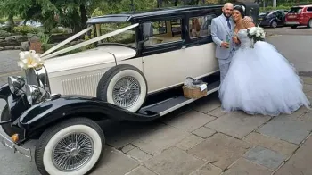 Bride and Groom standing by the siode of a Vintage Bramwwith decorated with ribbons