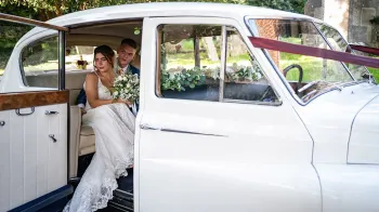 Inside rear photo taken from outside the vehicle with door open showing the Bride holding a bouquet of flowers