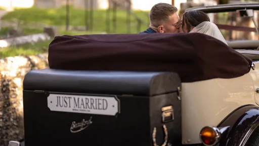 Rear view of Beauford Convertible with roof down showing Bride and Groom kissing