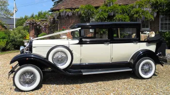Left Side view of Branford Vintage car showing the spare wheel mounted on the left wing, white wall tires and white ribbons on front bonnet.