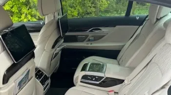 rear interior seating of 7-series BMW with cream leather interior and TV Display