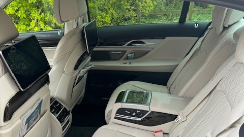 rear interior seating of 7-series BMW with cream leather interior and TV Display