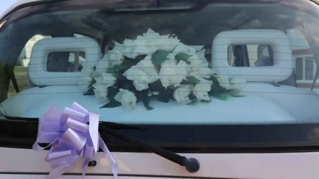 Wedding Flowers on rear parcel shelf viewed from outside through the rear window, Light Purple Bow attached to windscreen wiper