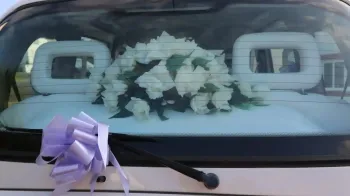 Wedding Flowers on rear parcel shelf viewed from outside through the rear window, Light Purple Bow attached to windscreen wiper