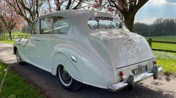 Rear view of Classic Austin Princess Limousine in a gravel path with green field and trees in the background