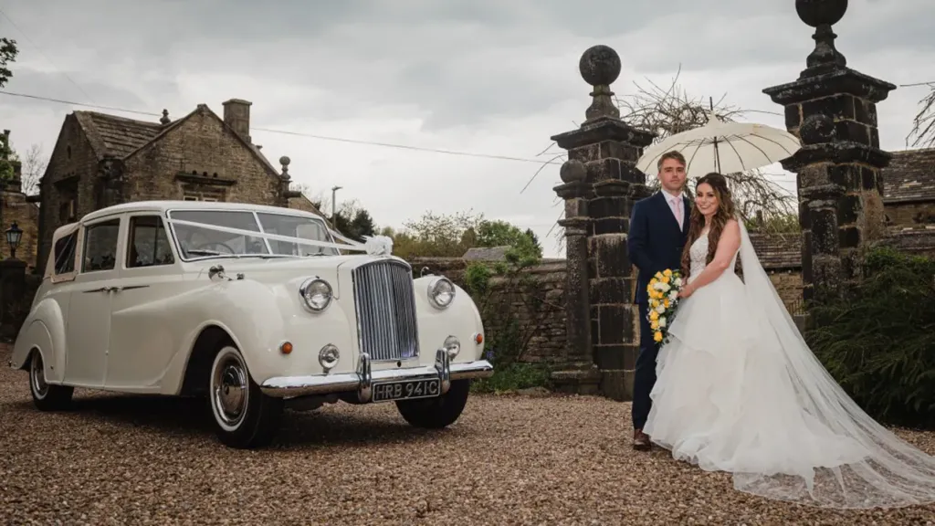 Bride and Groom stansing in front of the classic Austin Princess Limousine
